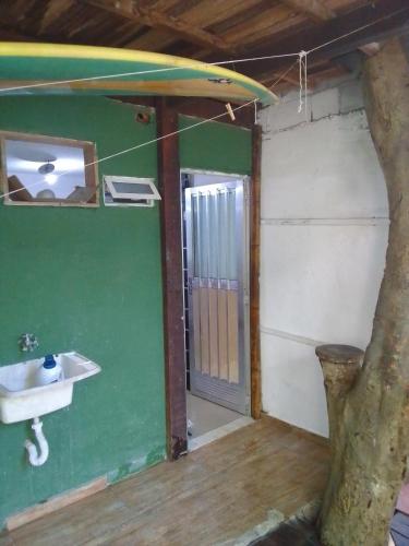 uma casa de banho com um lavatório e uma prancha de surf na parede em Kitnet na praia da Macumba no morro do Rangel no Rio de Janeiro