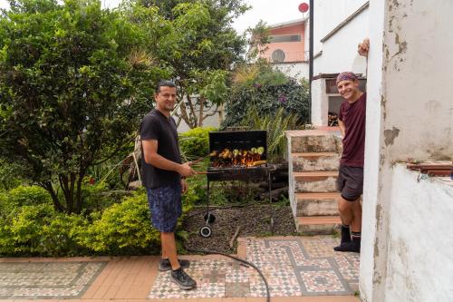 two men standing in a yard with a grill at B&B - Trekking y Senderismo in Choachí