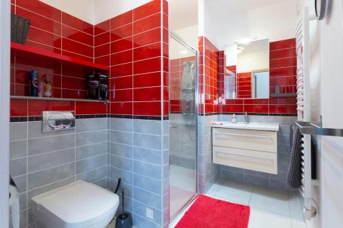 La salle de bains est pourvue de carrelage rouge, de toilettes et d'une douche. dans l'établissement Logement 2 chambres tout confort Nimes, à Nîmes