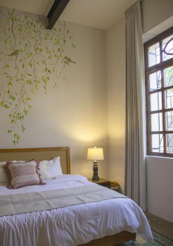 a bedroom with a bed with a tree mural on the wall at Casa Santa Ana Centro Mérida in Mérida