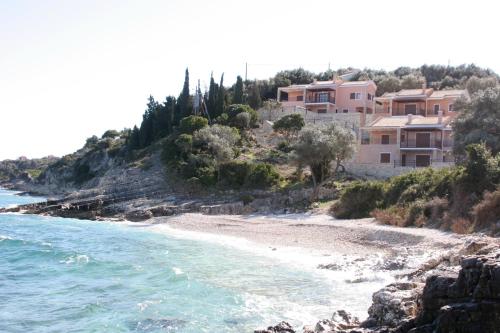 une plage avec des maisons sur une colline à côté de l'eau dans l'établissement Anassa Mare Villas & Residences, à Gaios