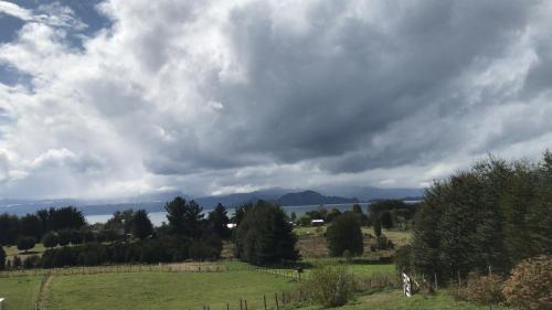 a cloudy sky over a green field with trees at Parcela de Agrado "Entre Lagos y Volcanes" in Puyehue