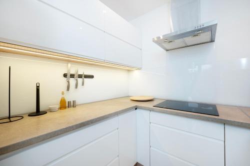 a kitchen with white cabinets and a counter top at Tabelowa Deluxe Apartament with Garden in Łódź