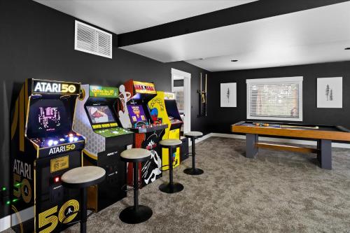 a room with arcade games and a table and stools at Luxe Lakeside New Build by Flathead Lake Speakeasy in Somers