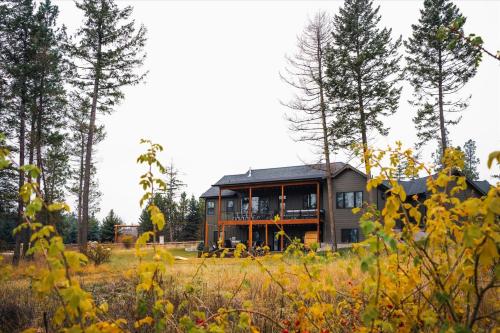 a house in the middle of a field with trees at Luxe Lakeside New Build by Flathead Lake Speakeasy in Somers