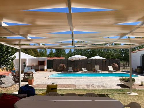 a swimming pool with a large blue and white umbrella at Quinta do Mastim in Évora