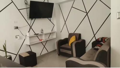 ein Wohnzimmer mit zwei Stühlen und einem Flachbildfernseher in der Unterkunft MINI DPTO 302 PISO 3 - Consultar Cochera in Tacna