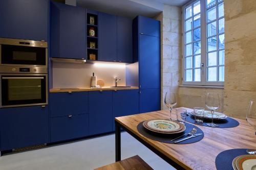 une cuisine avec des placards bleus et une table en bois dans l'établissement Appartement Vivier - les suites du palais, parking privé, vue cathédrale,2 chambres, by PRIMO C0NCIERGERIE, à Nevers