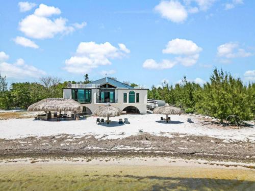 a house with some straw umbrellas on a beach at Ocean Depth Room at Barnacle Resort in Big Pine Key