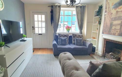a living room with a blue couch and a tv at Inviting 2-Bed Cottage in Windsor in Windsor