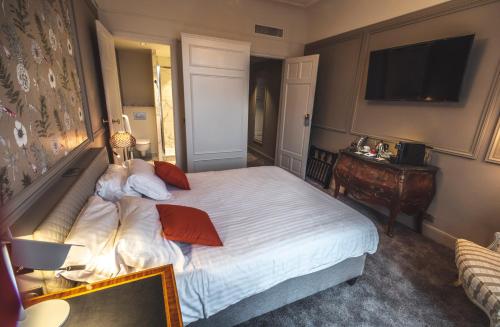 a bedroom with a bed and a desk and a television at Grand Hotel Bellevue - Grand Place in Lille