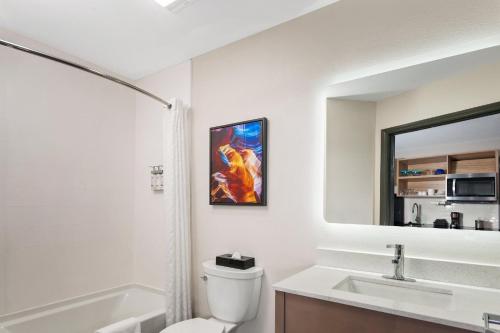 a bathroom with a toilet and a sink and a mirror at Candlewood Suites Harrisonburg by IHG in Harrisonburg