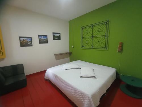 a bedroom with a white bed in a green wall at Golden Frog Manizales in Manizales