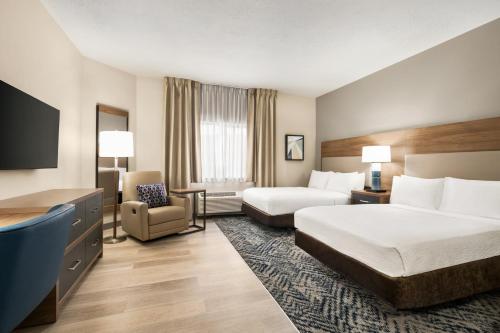 a hotel room with two beds and a chair at Candlewood Suites Boise - Towne Square by IHG in Boise