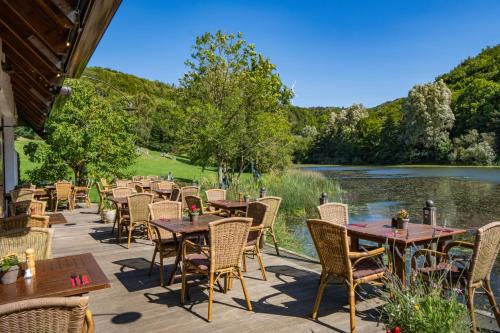 a patio with tables and chairs next to a river at Hotel-Restaurant Eifeler Seehütte in Rieden