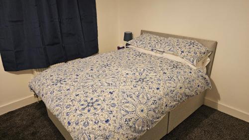 a bedroom with a bed with a blue and white comforter at Ensuite Double Room in City Of Oxford in Oxford