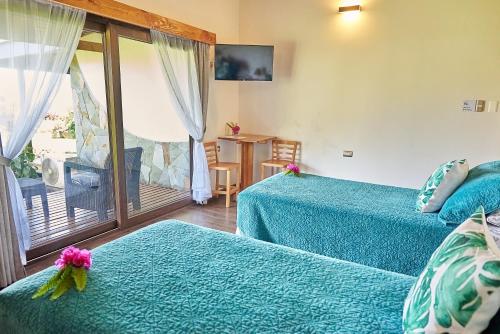 a hotel room with two beds and a balcony at Takarua Lodge in Hanga Roa