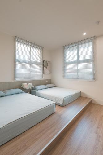 two beds in a room with two windows at 苒得出門 - 台南包棟民宿 in Tainan