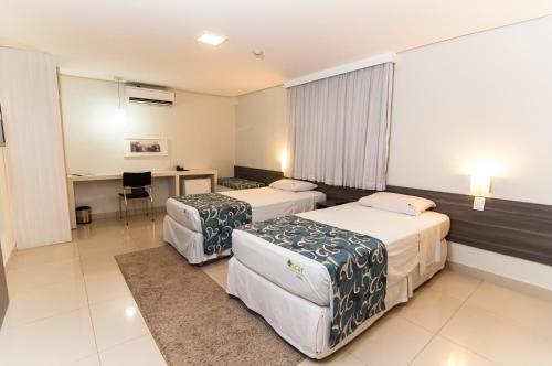 a hotel room with two beds and a desk at Oscar Hotel Executive in Porto Velho