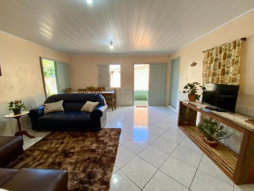 a living room with a couch and a tv at Casa acolhedora ideal para famílias, com Wi-Fi rápido, cozinha exclusiva e equipada, varanda com churrasqueira - A apenas 1 km da praia do bairro e 5 km da charmosa Praia da Vila in Imbituba