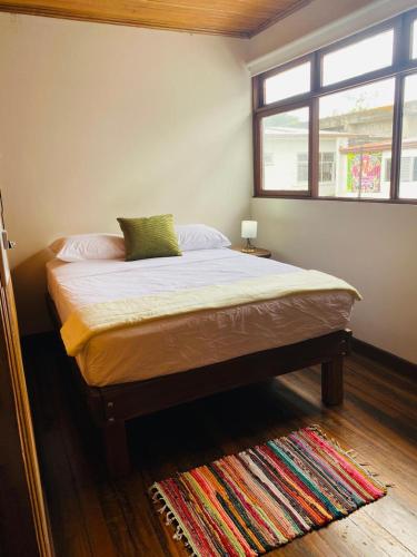 a bed in a bedroom with a window and a rug at Casa 1856- cómodas habitaciones en el Centro de Alajuela in Alajuela City