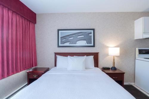 a large bed in a hotel room with a red window at Sandman Hotel Penticton in Penticton