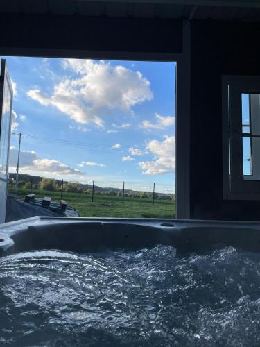a bath tub with a view of a field at La Béroline, maison avec jacuzzi près de Honfleur in Conteville