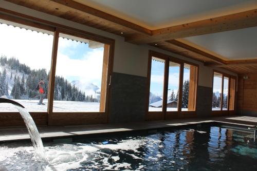 a house with a swimming pool with a view of the mountains at Hôtel Restaurant "Les Sapins" Wellness & Gourmet in Manigod