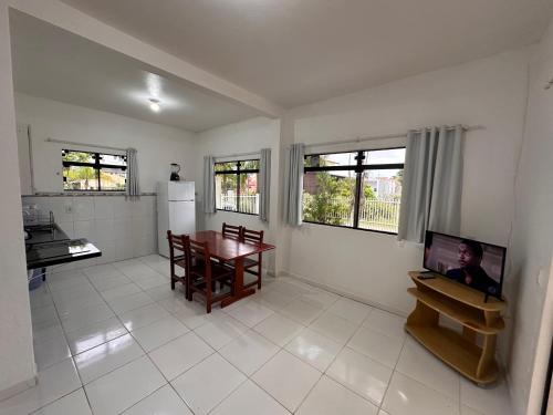 a kitchen and dining room with a table and a television at Apartamentos Praia do Sonho in Palhoça