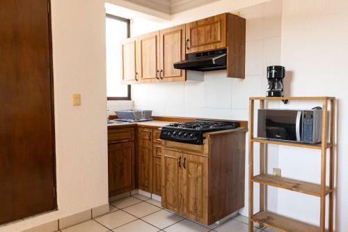 a small kitchen with wooden cabinets and a microwave at Bohemian Loft Xochimilco Neighborhood - 1 Bed in Oaxaca City