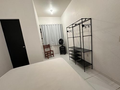 a bedroom with a black book shelf and a room with a bed at Apartamentos Praia do Sonho in Palhoça