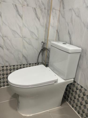 a white toilet in a bathroom with a tiled wall at ระเบียงเลเกาะลิบง โฮมสเตย์ in Ko Libong