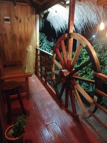 a large wooden wagon wheel sitting on a porch at Cabañas Compartidas en Casa Quinta en Itá in Itauguá