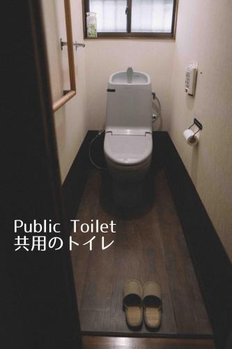 a bathroom with a toilet and two pairs of shoes at yururito guesthouse in Matsumoto