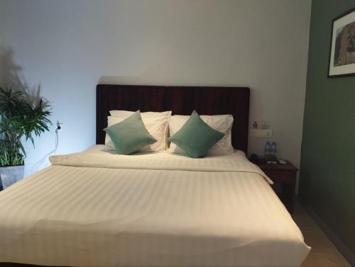 a bedroom with a large bed with green and white pillows at Phnom Meas Homestay in Sisophon 