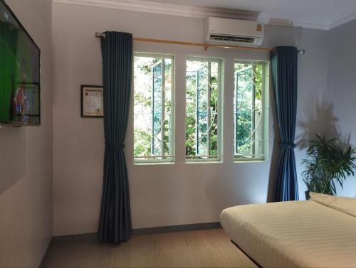 a bedroom with blue curtains and a window at Phnom Meas Homestay in Sisophon 