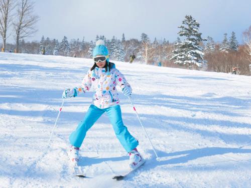 a young girl is skiing down a snow covered slope at Labo Land Kurohime in Shinano