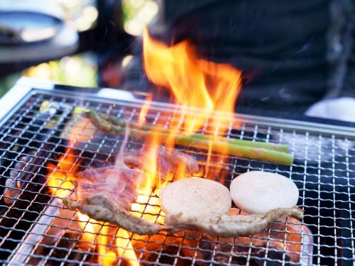 a grill with three hamburgers and meat on fire at Labo Land Kurohime in Shinano