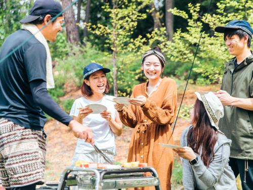 a group of people standing around a grill at Labo Land Kurohime in Shinano