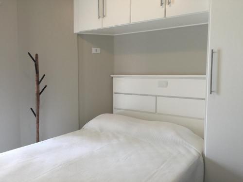 a white bedroom with a bed and white cabinets at Apartamento Vereda Tropical in Guarujá