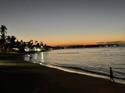 a person walking on the beach at sunset at Luxury 2 Bedroom Apartment, 1 Min Walk to Punta Popy Beach, Pool, AC, Fast WiFi, Las Terrenas in Las Terrenas