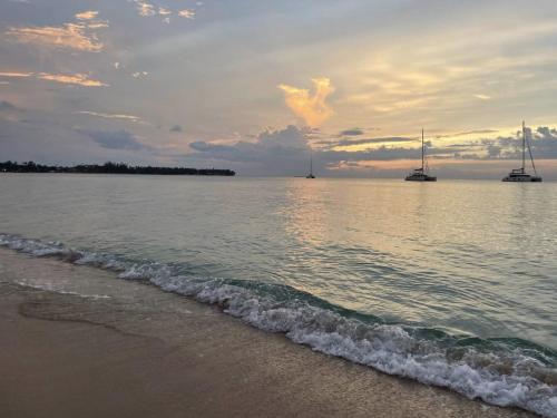 a beach with boats in the water with a cloudy sky at Luxury 2 Bedroom Apartment, 1 Min Walk to Punta Popy Beach, Pool, AC, Fast WiFi, Las Terrenas in Las Terrenas
