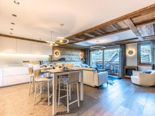 Il dispose d'une cuisine ouverte et d'un salon avec une table et des chaises. dans l'établissement Appartement skis aux pieds avec accès SPA, conciergerie 5*, balcon orienté Ouest - FR-1-613-54, à Les Allues