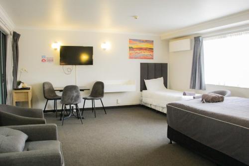 a hotel room with a bed and a table and chairs at Anchorage Motor Lodge in Napier