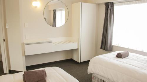 a white room with a mirror and a bed and a mirror at Anchorage Motor Lodge in Napier