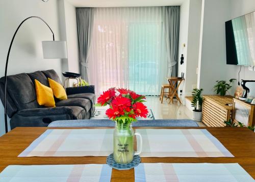 a living room with a vase with red flowers on a table at Borbaimai home in Chiang Rai