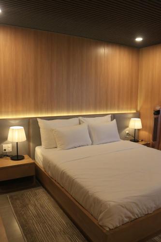 a bedroom with a large white bed with two lamps at Lavender Dalat Hotel and Resorts in Da Lat