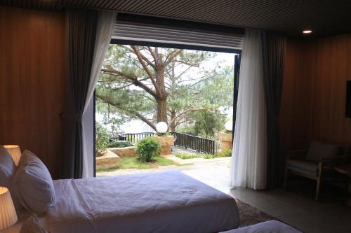 a bedroom with a bed and a large window at Lavender Dalat Hotel and Resorts in Da Lat