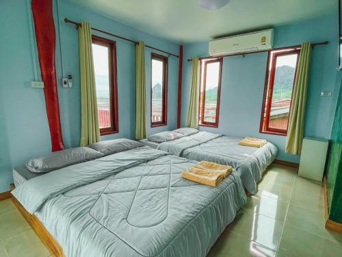 two beds in a room with blue walls and windows at ระเบียงเลเกาะลิบง โฮมสเตย์ in Ko Libong