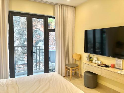 a bedroom with a large television and a balcony at Hanoi’s Lane Homestay in Hanoi
